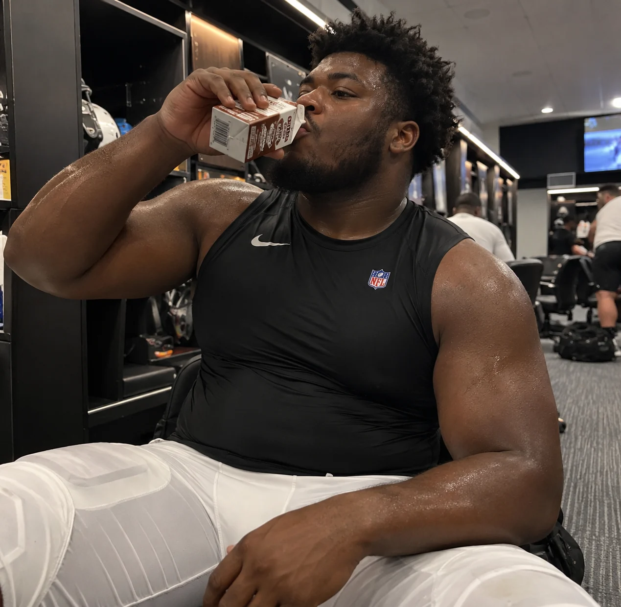 Football player drinking a carton of chocolate milk in a locker room after activity